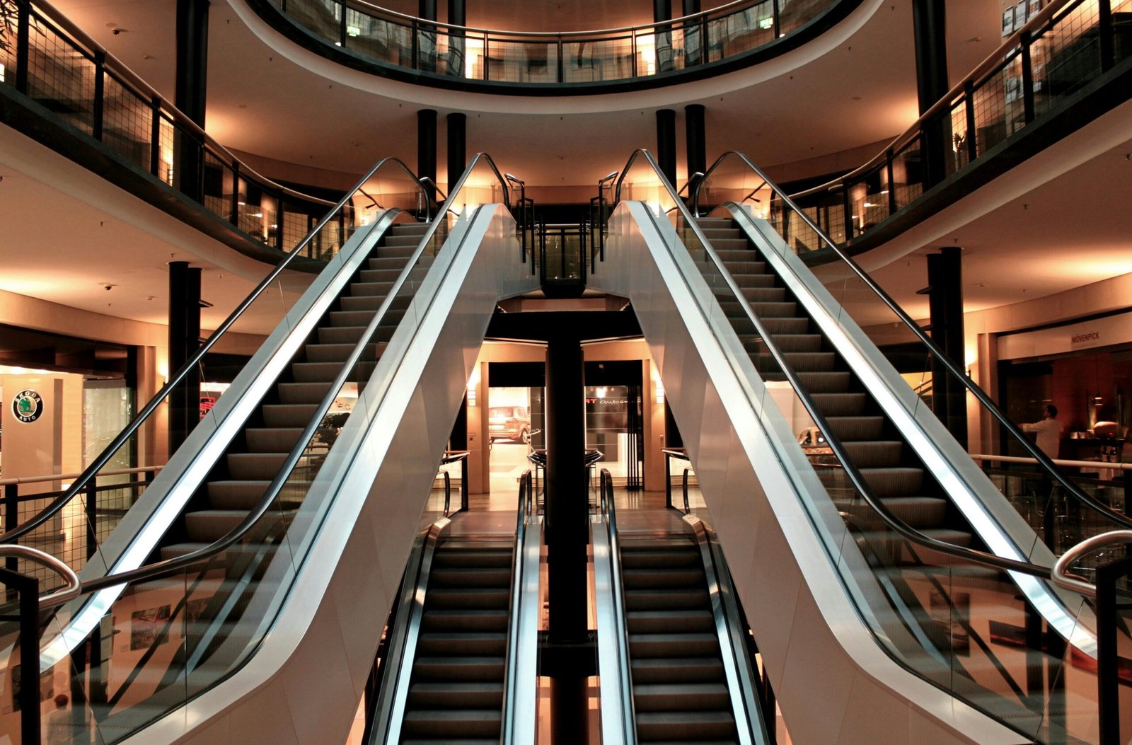 Symmetrical view of escalators in a modern shopping mall interior, showcasing architecture and design.