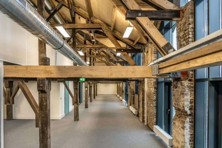Spacious industrial loft with exposed wooden beams and ductwork, showcasing modern architecture.