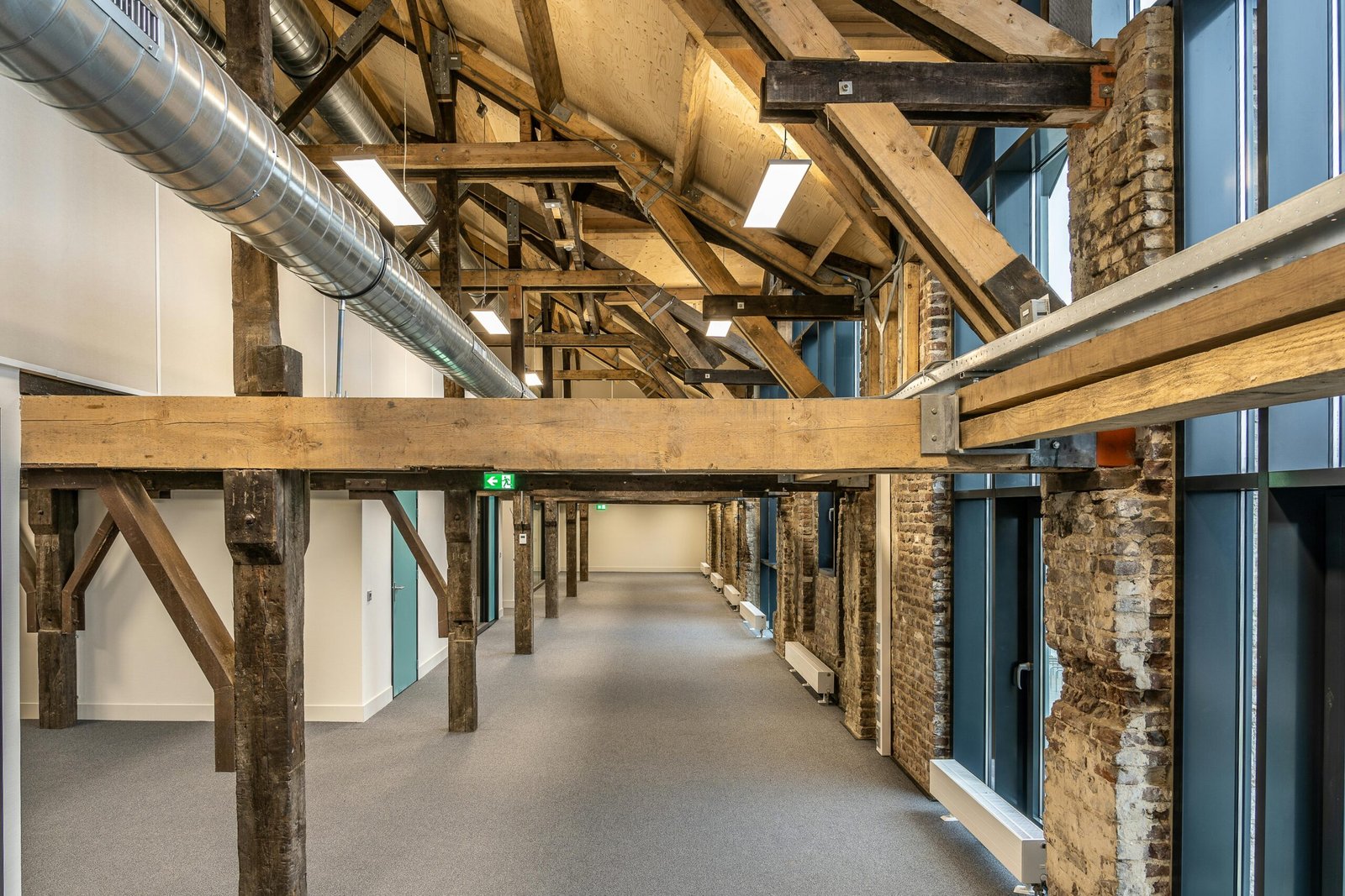 Spacious industrial loft with exposed wooden beams and ductwork, showcasing modern architecture.